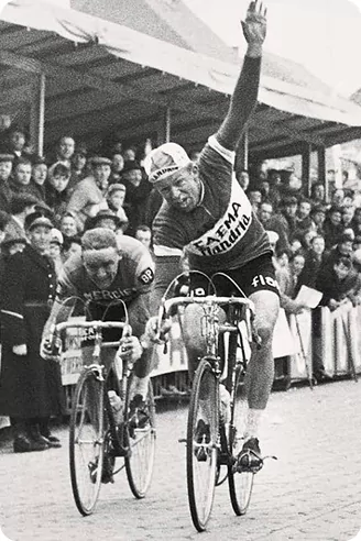 Photo historique en noir et blanc d’un coureur Flandria qui lève le bras à l’arrivée d’une course